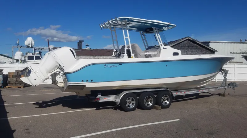 Slide: The Image of 2018 Edgewater 320 CC boat on trailer, blue hull, parked outdoors. - 1