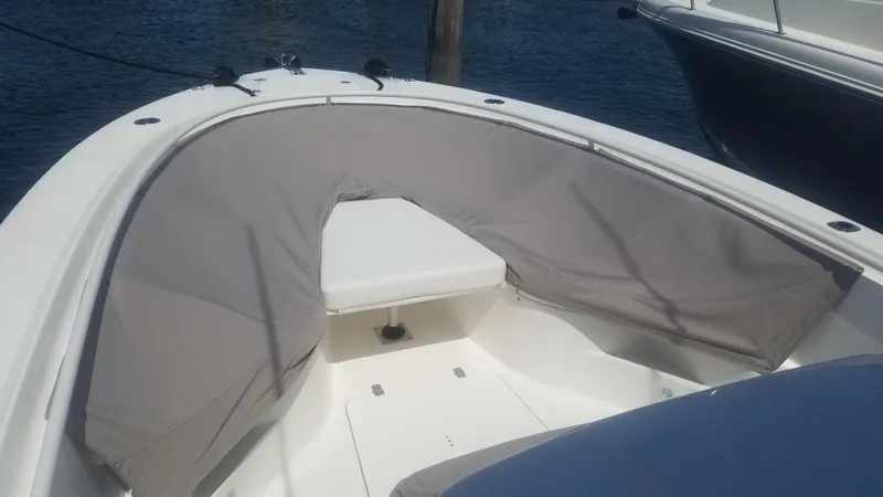 Slide: The Image of 2018 Edgewater 320 CC boat interior with cushioned seating, docked by the water. - 13