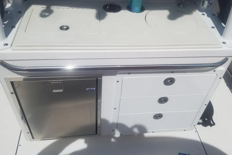 Slide: The Image of 2018 Edgewater 320 CC boat console with storage drawers and stainless steel fridge. - 18