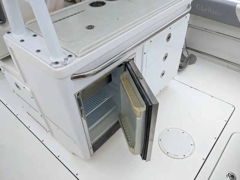 Slide: The Image of 2018 Edgewater 320 CC boat with open mini fridge and storage compartments. - 24