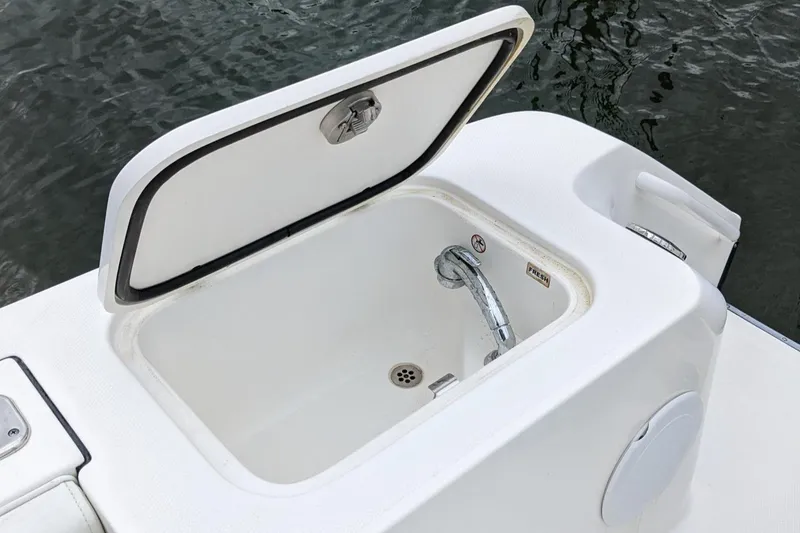 Slide: The Image of Open storage compartment on 2018 Edgewater 320 CC boat, featuring a built-in faucet. - 27