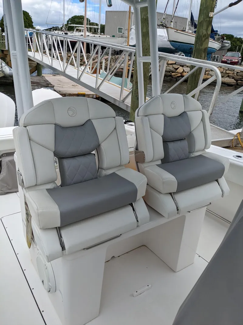Slide: The Image of 2018 Edgewater 320 CC boat seats, docked at marina with boats in background. - 9