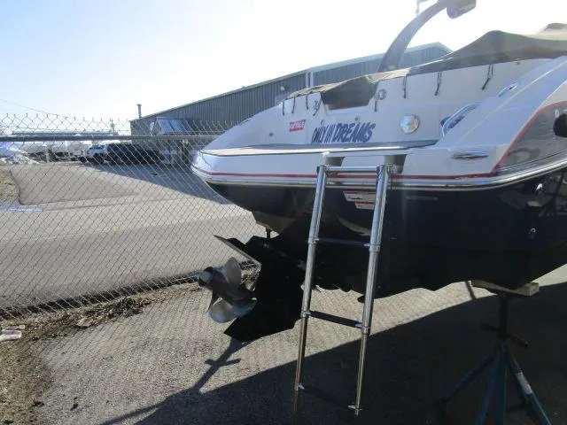 Slide: The Image of 2017 Larson 292 LXI boat with ladder, parked near a chain-link fence. - 34