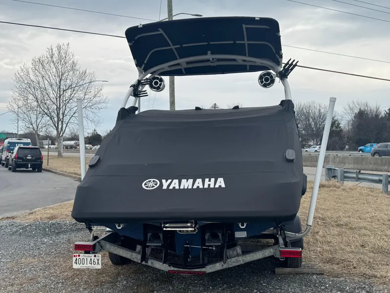 Slide: The Image of 2023 Yamaha Boats 252SD covered on trailer, rear view, parked outdoors. - 2