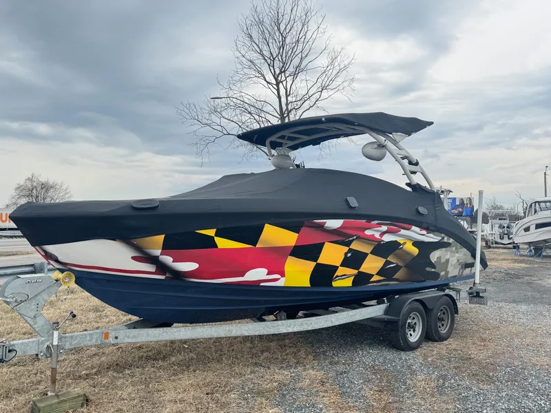 Slide: The Image of 2023 Yamaha Boats 252SD with vibrant design on a trailer, under cloudy sky. - 7
