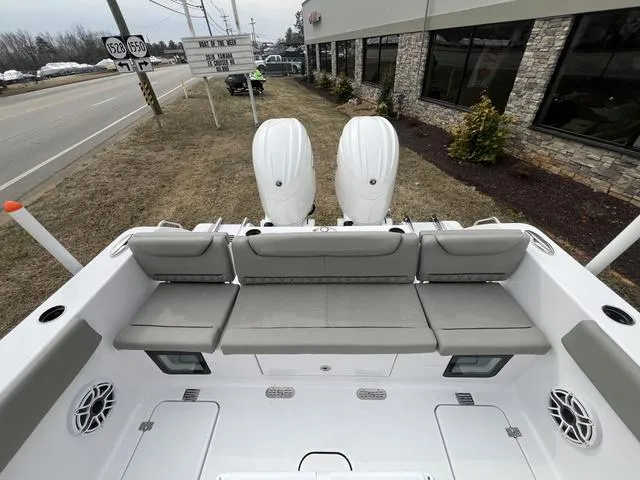 Slide: The Image of 2025 Sportsman Heritage 261 boat with dual engines and cushioned seating, parked near a road. - 16