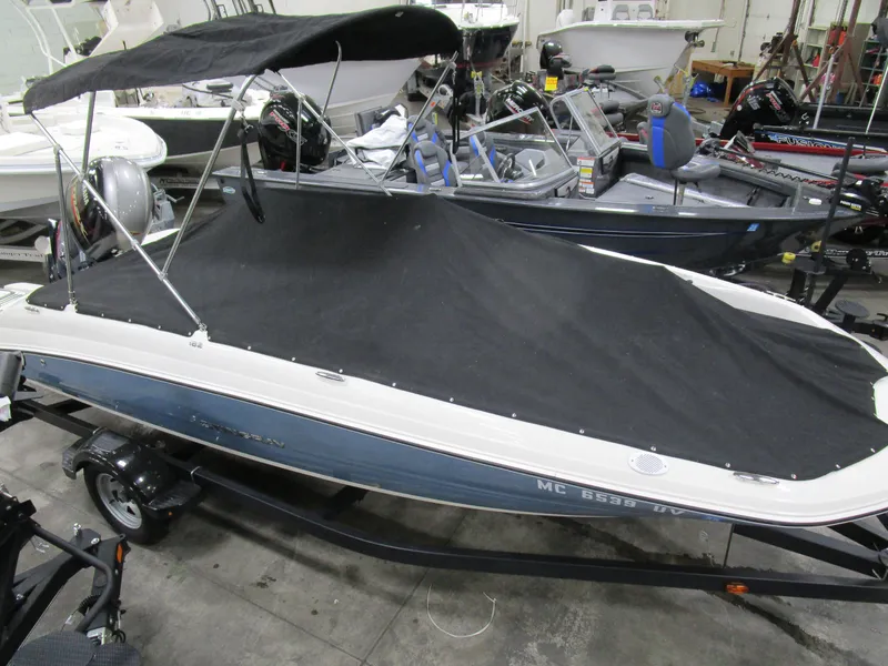 Slide: The Image of 2022 Stingray 182 boat with cover and canopy in showroom setting. - 18