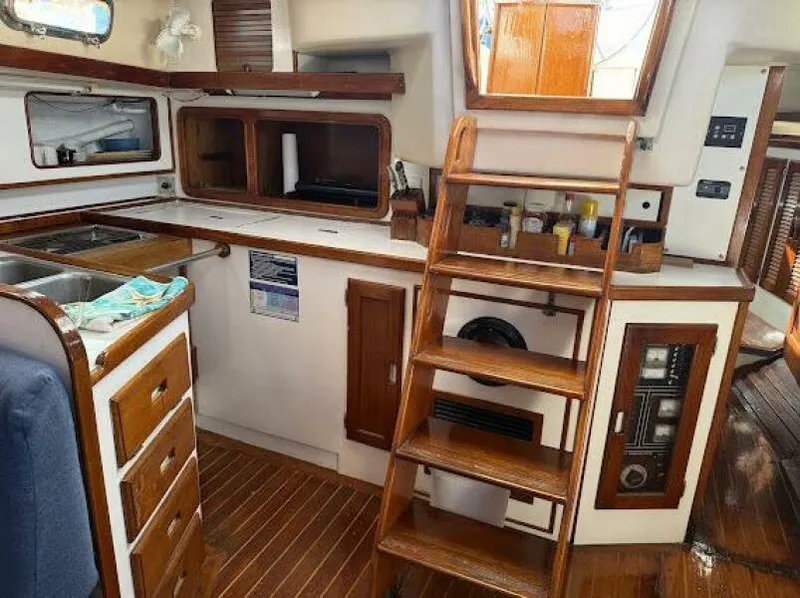 Slide: The Image of Interior of 1989 Catalina Morgan 440 sailboat, featuring wooden cabinetry and stairs. - 34