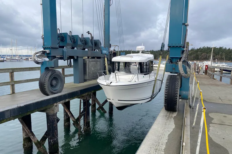 Slide: The Image of 2020 Jeanneau NC Sport 695 boat being lifted at a marina. - 13