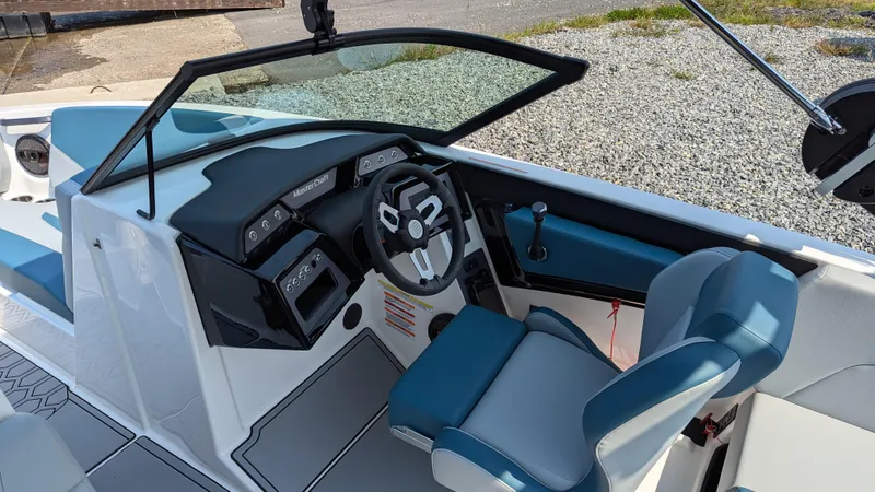 Slide: The Image of 2025 MasterCraft NXT23 boat interior with modern dashboard and blue seating. - 11