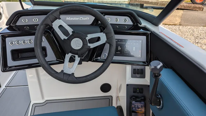 Slide: The Image of 2025 MasterCraft NXT23 boat dashboard with steering wheel and digital display. - 12