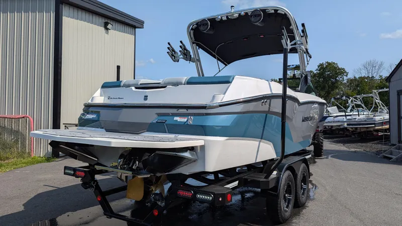 Slide: The Image of 2025 MasterCraft NXT23 boat on trailer, parked outdoors near a building. - 4