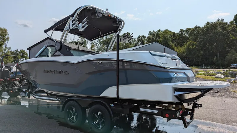 Slide: The Image of 2025 MasterCraft NXT23 boat on trailer, parked outdoors, showcasing sleek design and modern features. - 5