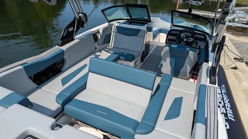 Slide: The Image of 2025 MasterCraft NXT23 boat interior with blue and white seating, docked by the water. - 9