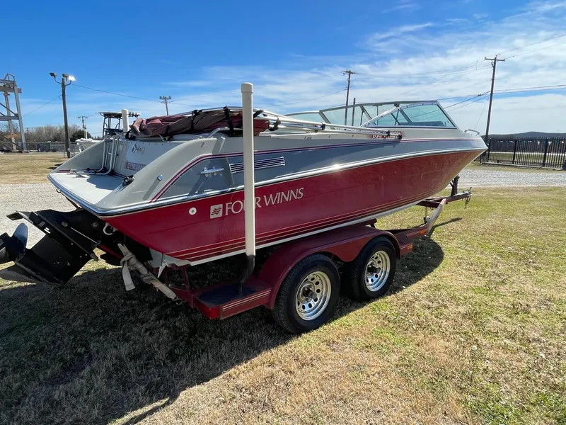 The Image of 1988 Four Winns 200 Horizon boat on trailer, red and white design, parked on grass. - 1