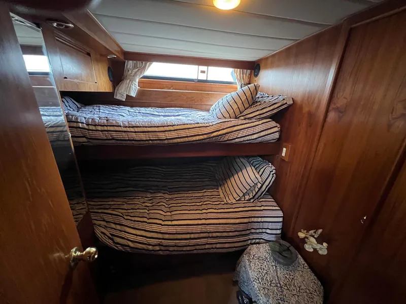 Slide: The Image of Cozy cabin with bunk beds in 1988 President Motor Yacht, featuring wood paneling and striped bedding. - 14