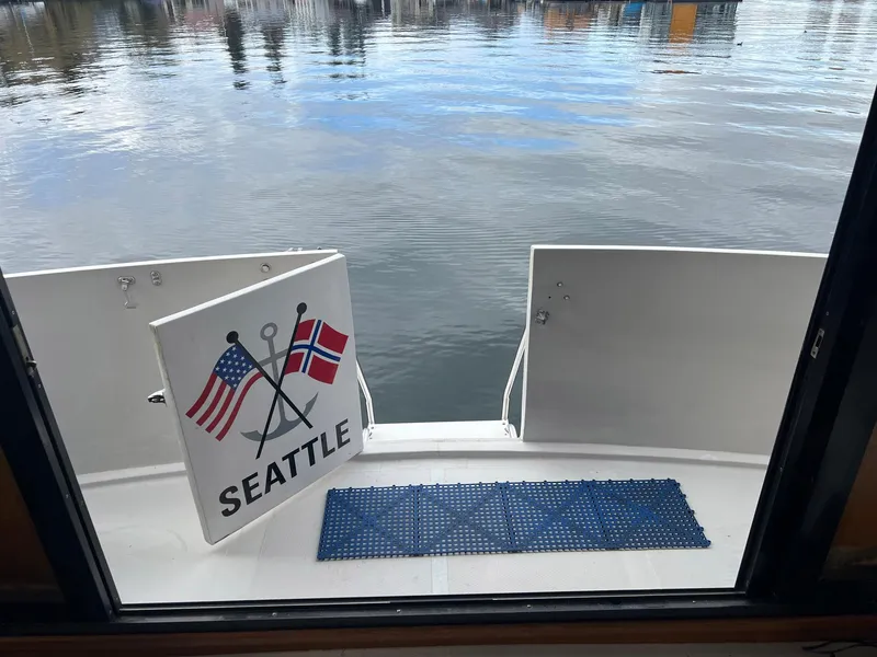 Slide: The Image of 1988 President Motor Yacht with Seattle sign, American and Norwegian flags, docked by calm water. - 22