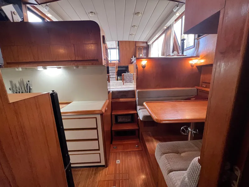 Slide: The Image of 1988 President Motor Yacht interior with wood paneling, dining area, and compact kitchen. - 7