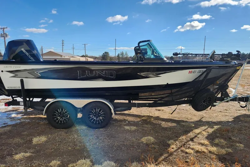 Slide: The Image of 2022 Lund 1975 Tyee Limited boat on trailer, parked outdoors under blue sky. - 4