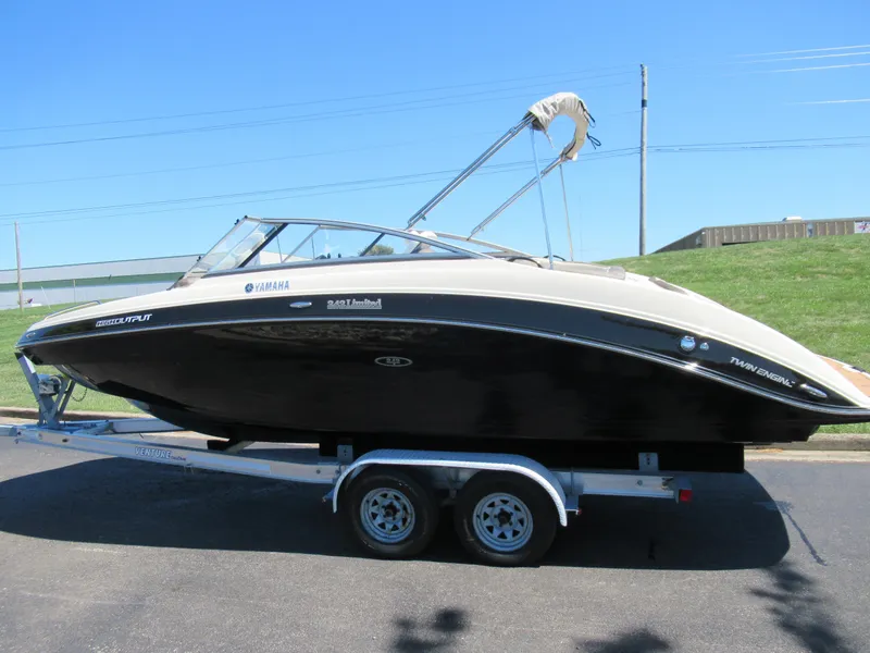 Slide: The Image of 2014 Yamaha Boats 242 Limited on trailer, sleek black design, sunny day. - 4