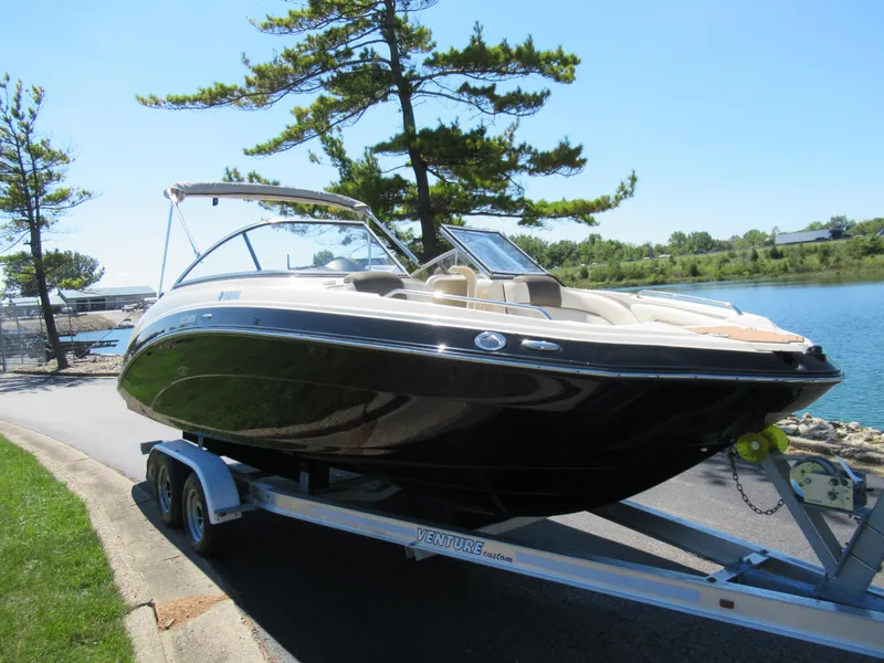 Slide: The Image of 2014 Yamaha Boats 242 Limited on trailer by a lakeside, under clear blue sky. - 8