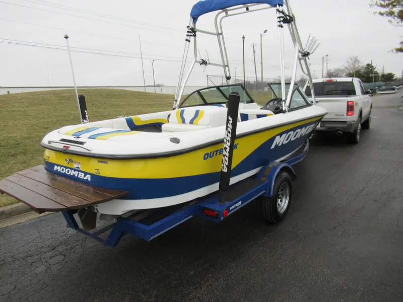 Slide: The Image of 2000 Moomba Outback LS boat on trailer, blue and yellow design, parked near a truck. - 3