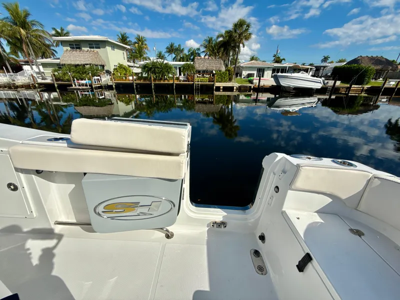 Slide: The Image of 2024 Sea Hunt Ultra 275 SE boat docked by a scenic waterfront. - 25