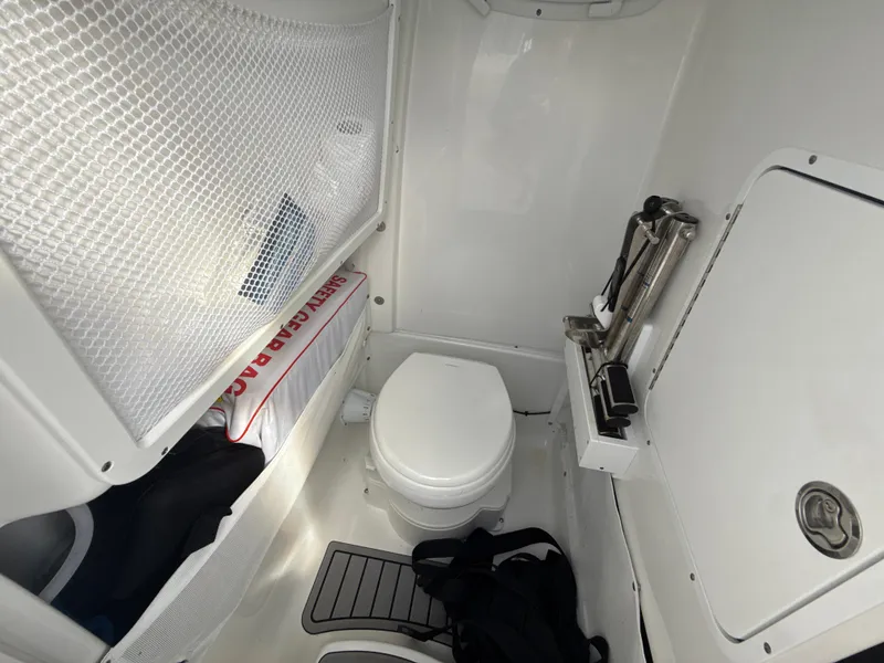 Slide: The Image of 2024 Sea Hunt Ultra 275 SE boat interior with toilet and storage area. - 26