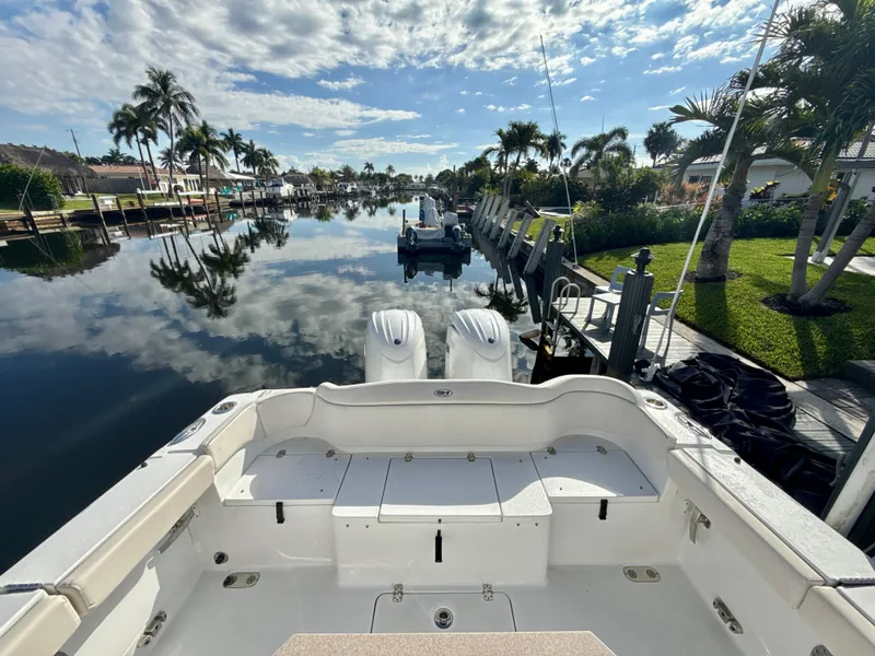 Slide: The Image of 2024 Sea Hunt Ultra 275 SE boat docked on a scenic, palm-lined canal. - 4