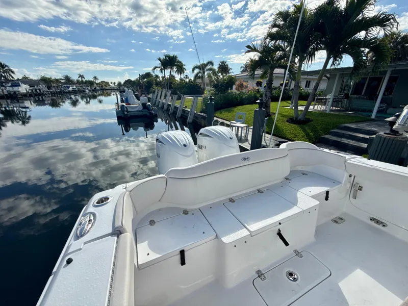 Slide: The Image of 2024 Sea Hunt Ultra 275 SE boat docked by a serene waterfront with palm trees. - 6