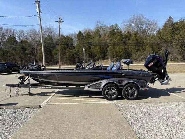 Slide: The Image of 2024 Ranger Z520R bass boat on trailer in parking lot, surrounded by trees. - 18