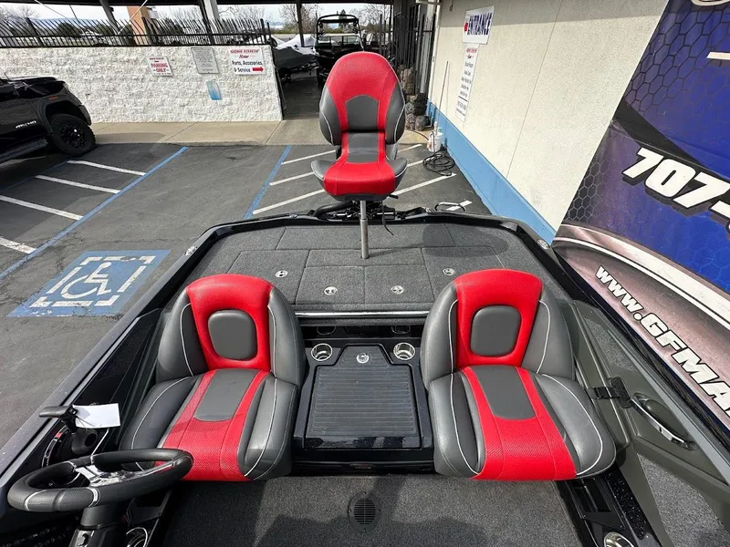 Slide: The Image of 2024 Ranger Z518 boat interior with red and gray seats, parked in a lot. - 14