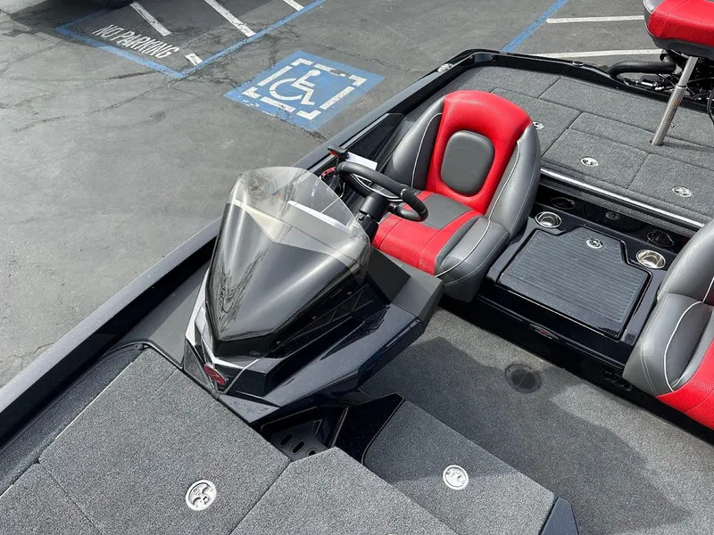 Slide: The Image of 2024 Ranger Z518 boat interior with red and gray seating, parked in a lot. - 24