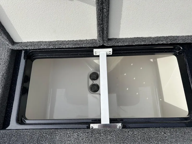 Slide: The Image of 2024 Ranger Z518 storage compartment with dual drainage holes, open lid, and carpeted edges. - 32