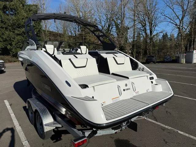 Slide: The Image of 2025 Yamaha Boats 222SD on trailer, parked in a lot with trees in the background. - 3