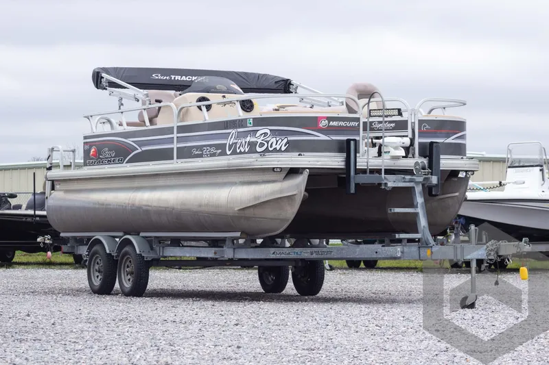 Slide: The Image of 2015 Sun Tracker Fishin' Barge 22 DLX pontoon boat on trailer, outdoor setting. - 3