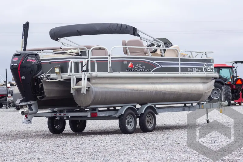 Slide: The Image of 2015 Sun Tracker Fishin' Barge 22 DLX pontoon boat on trailer, outdoor setting. - 4