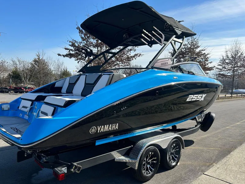 Slide: The Image of 2023 Yamaha Boats 255XD in blue and black on a trailer, parked outdoors. - 2