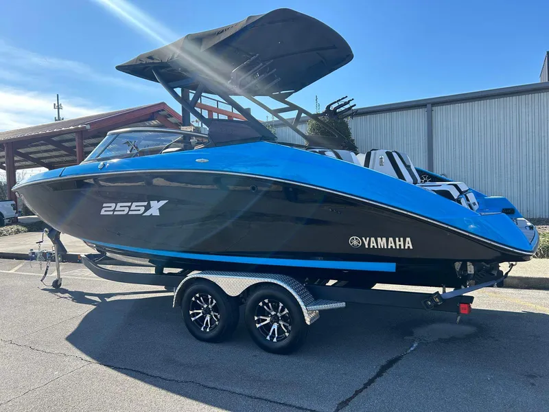 Slide: The Image of 2023 Yamaha Boats 255XD, blue and black, on a trailer, parked outdoors. - 3