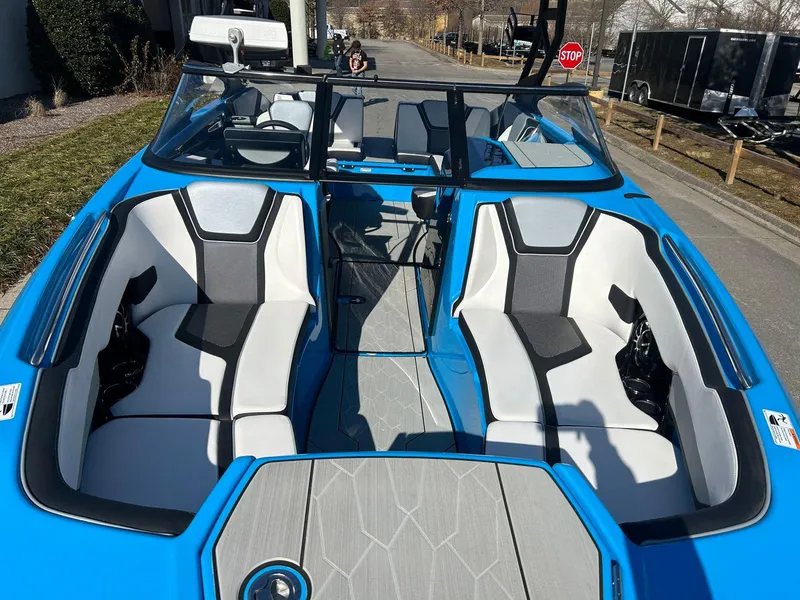Slide: The Image of 2023 Yamaha Boats 255XD interior with blue and white seating, docked on a sunny day. - 7