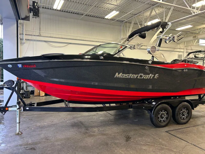 Slide: The Image of 2020 MasterCraft X22 boat with black and red design on a trailer in a garage. - 0