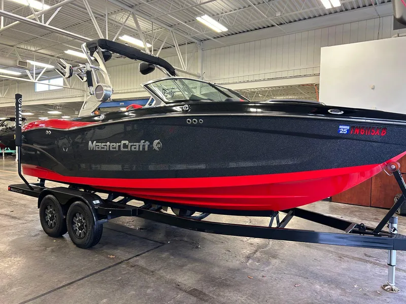 Slide: The Image of 2020 MasterCraft X22 boat with black and red design on a trailer in a showroom. - 1