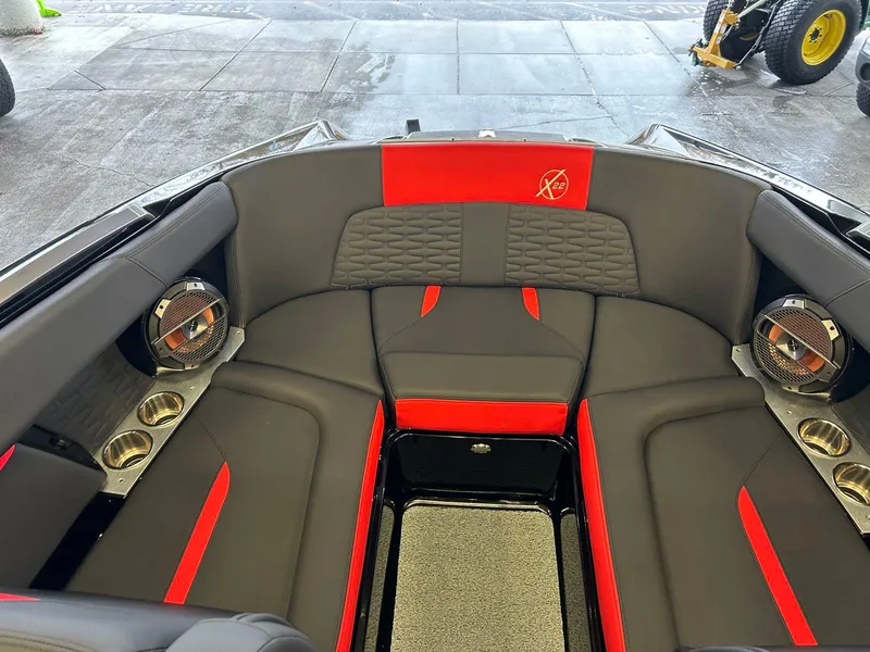 Slide: The Image of 2020 MasterCraft X22 boat interior with red and black seating, cup holders, and speakers. - 13