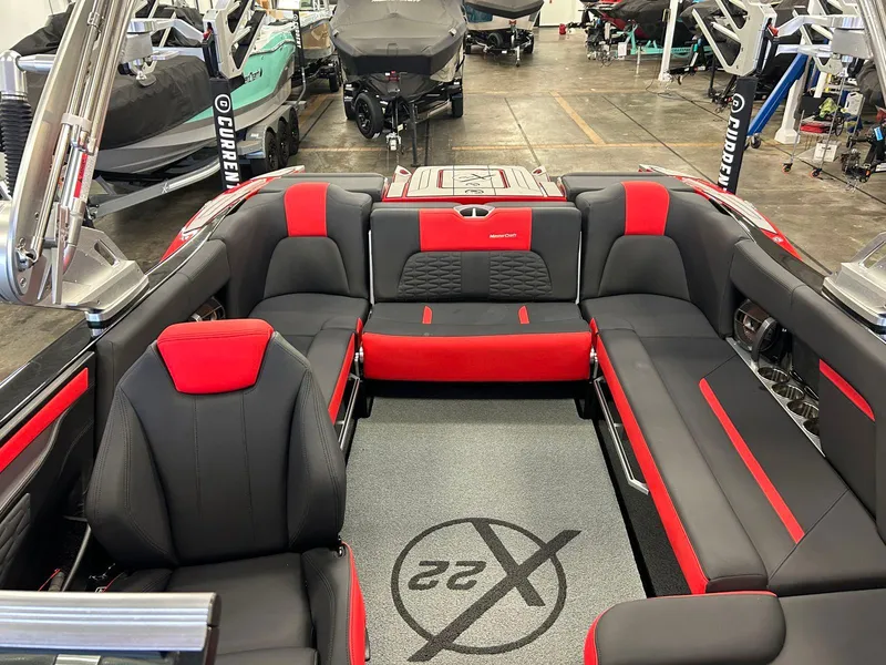 Slide: The Image of 2020 MasterCraft X22 boat interior with red and black seating in a showroom. - 14