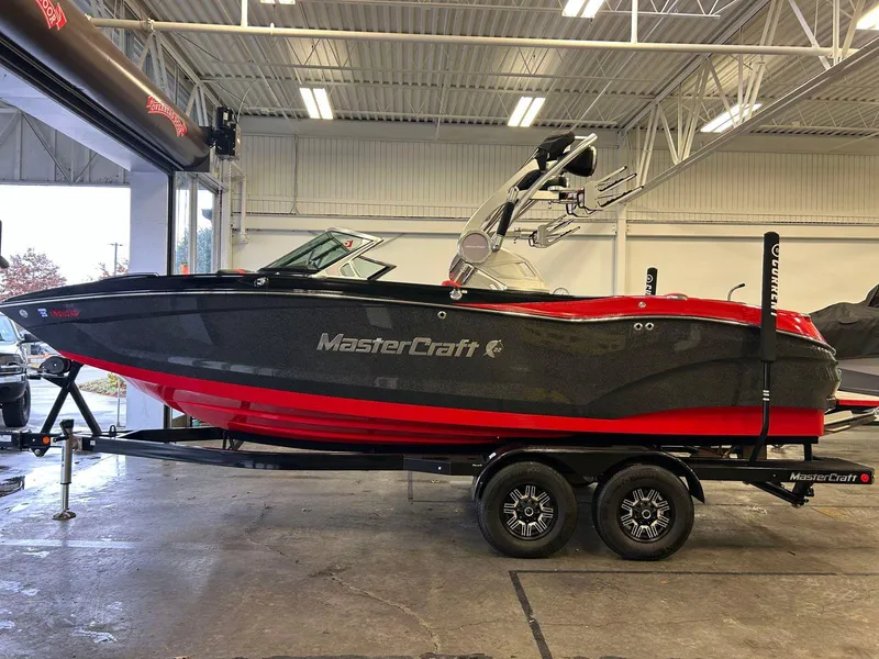 Slide: The Image of 2020 MasterCraft X22 boat in showroom, black and red design, on trailer. - 5