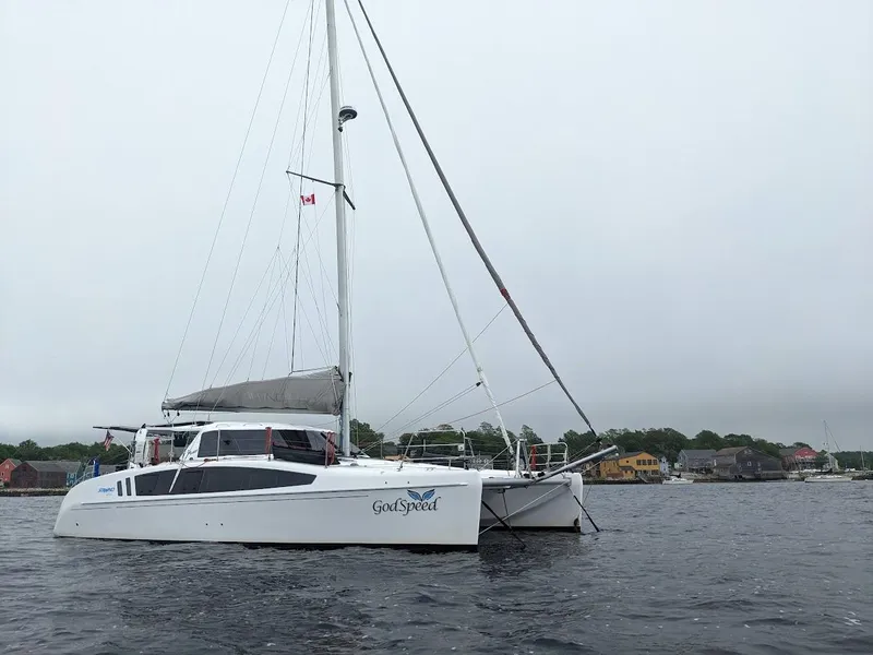 Slide: The Image of 2020 Seawind 1260 catamaran sailing on calm waters near a coastal town. - 1