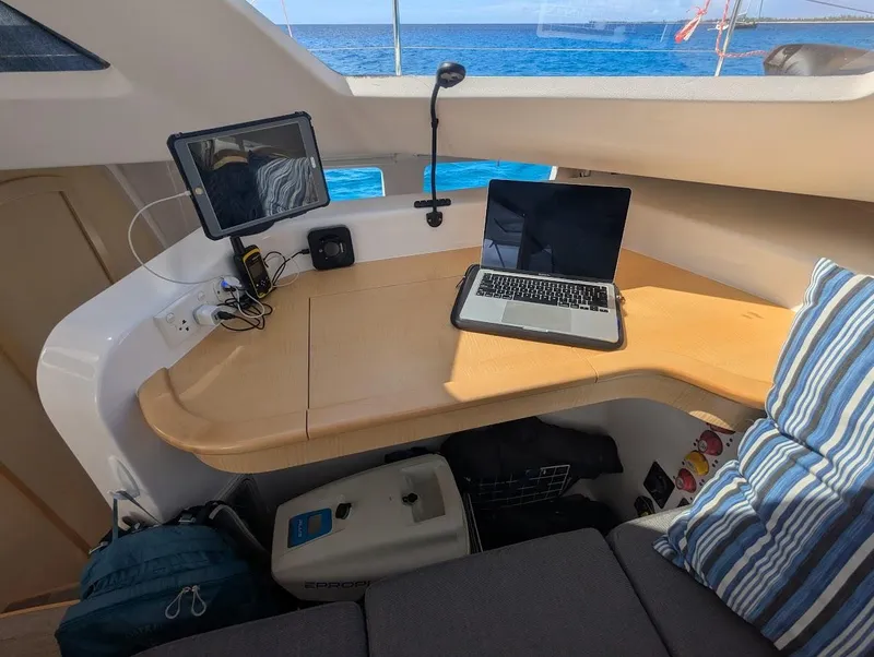 Slide: The Image of Seawind 1260 catamaran interior with laptop and tablet on wooden desk, ocean view. - 16