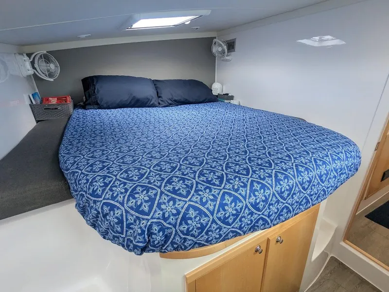 Slide: The Image of 2020 Seawind 1260 cabin with blue patterned bedding and storage underneath. - 24