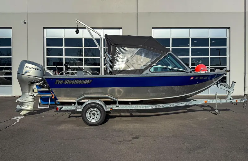 Slide: The Image of 2011 Pro-Steelheader 18 Sea Predator OS boat on trailer, parked outside a building. - 2