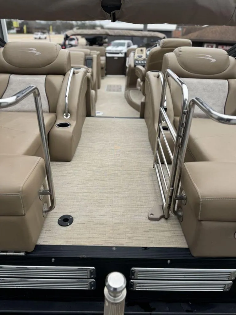 Slide: The Image of 2016 Bennington 2575 QCW I/O boat interior with beige seating and metal railings. - 11